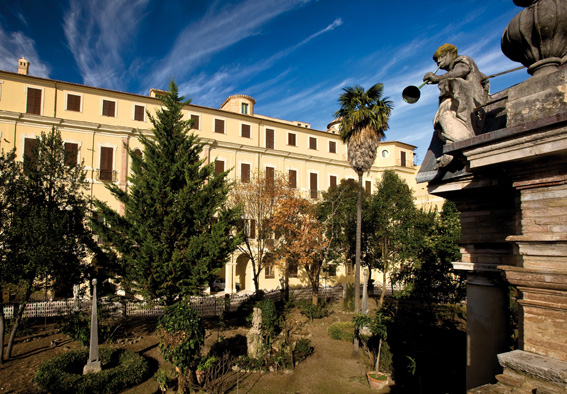 Giardino interno con sculture e angelo con tromba. Vista della facciata interna del palazzo